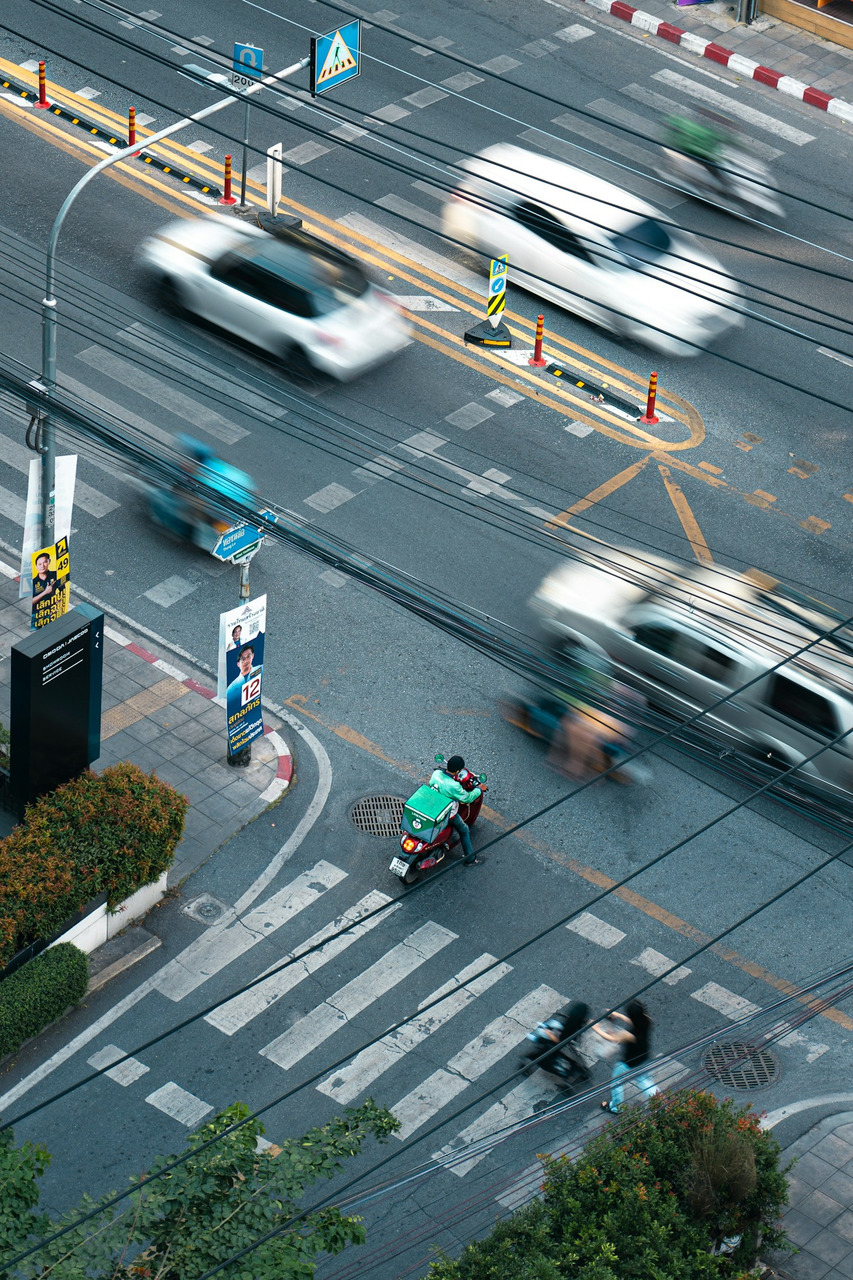 A delivery scooter on a city street with blurred traffic in motion, Ultra