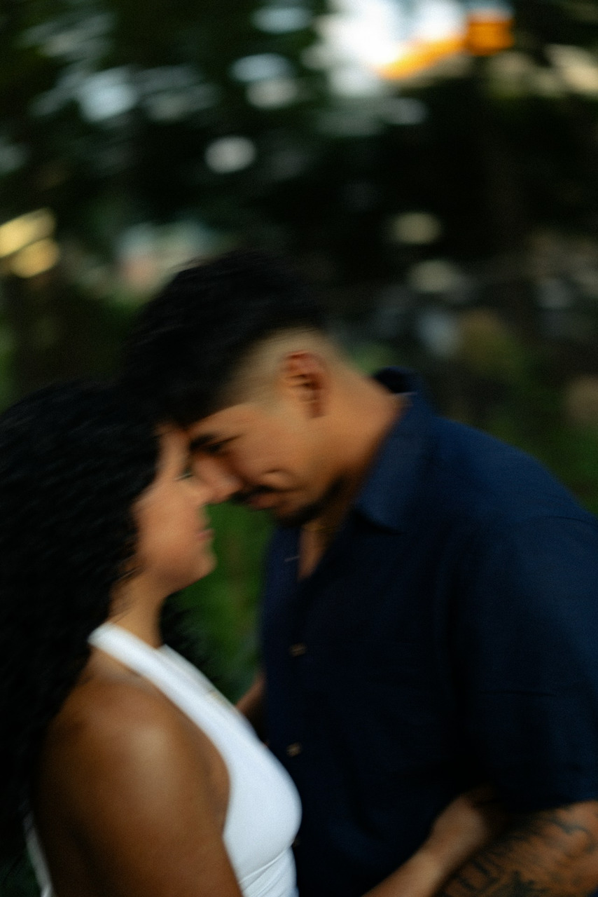 A man and a woman with foreheads touching in a soft-focus outdoor setting, Ultra