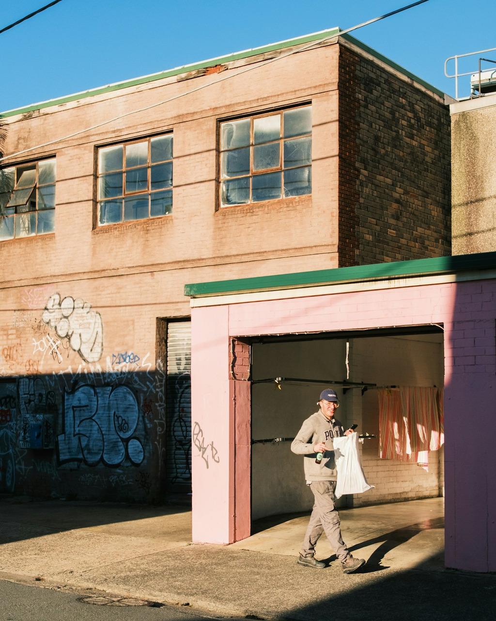 A man walks past a pink building in strong sunlight, Ultra