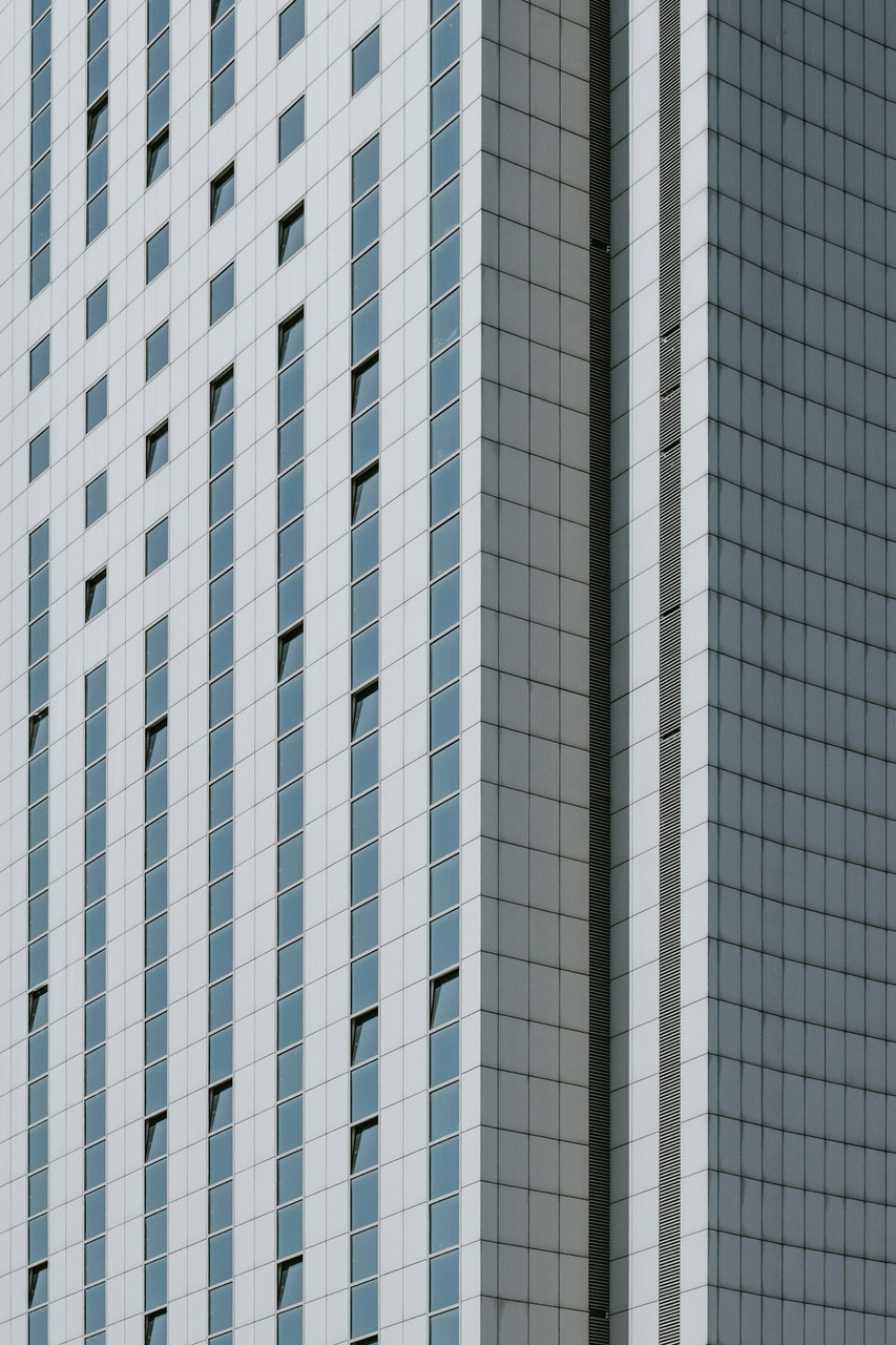 A modern skyscraper facade with grid patterns of square windows and grey panels, Ultra
