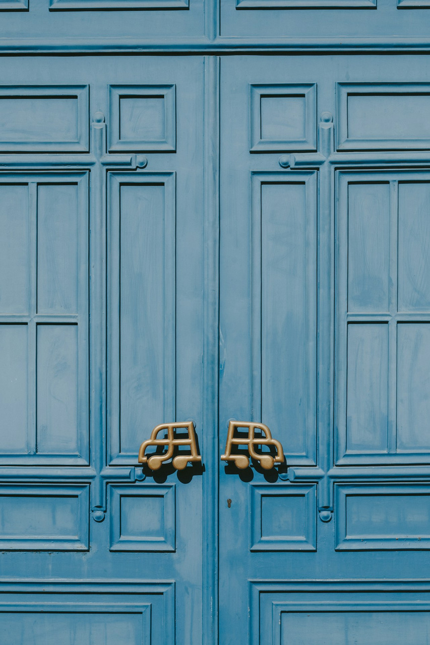 A pair of blue double doors with unique gold car-shaped door handles, Ultra