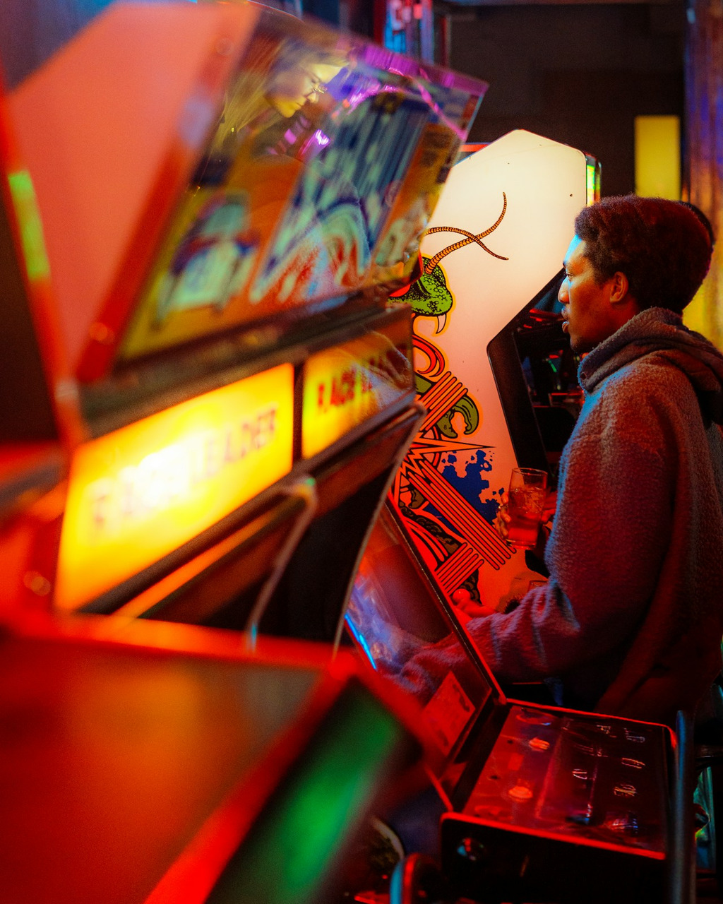 A person in a grey fleece hoodie playing a vintage arcade game, Ultra