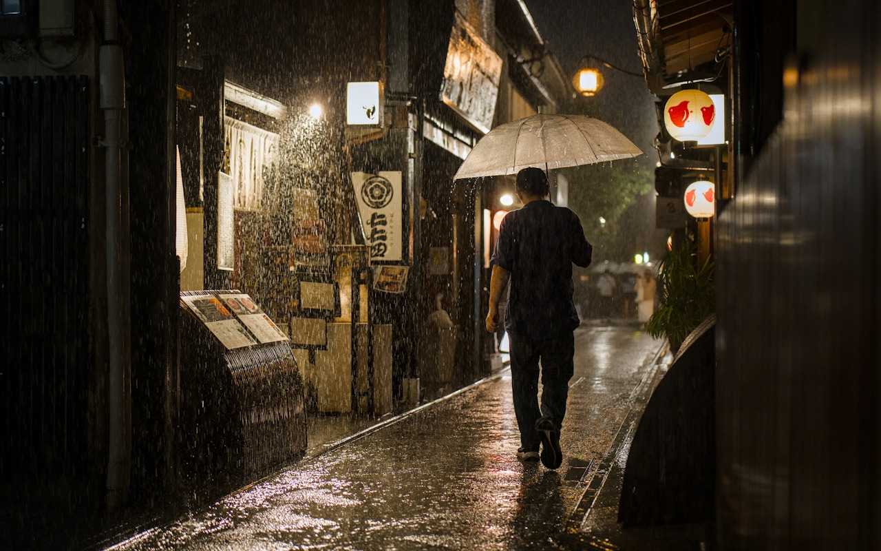 A person walks rainy street at night holding an umbrella, Ultra
