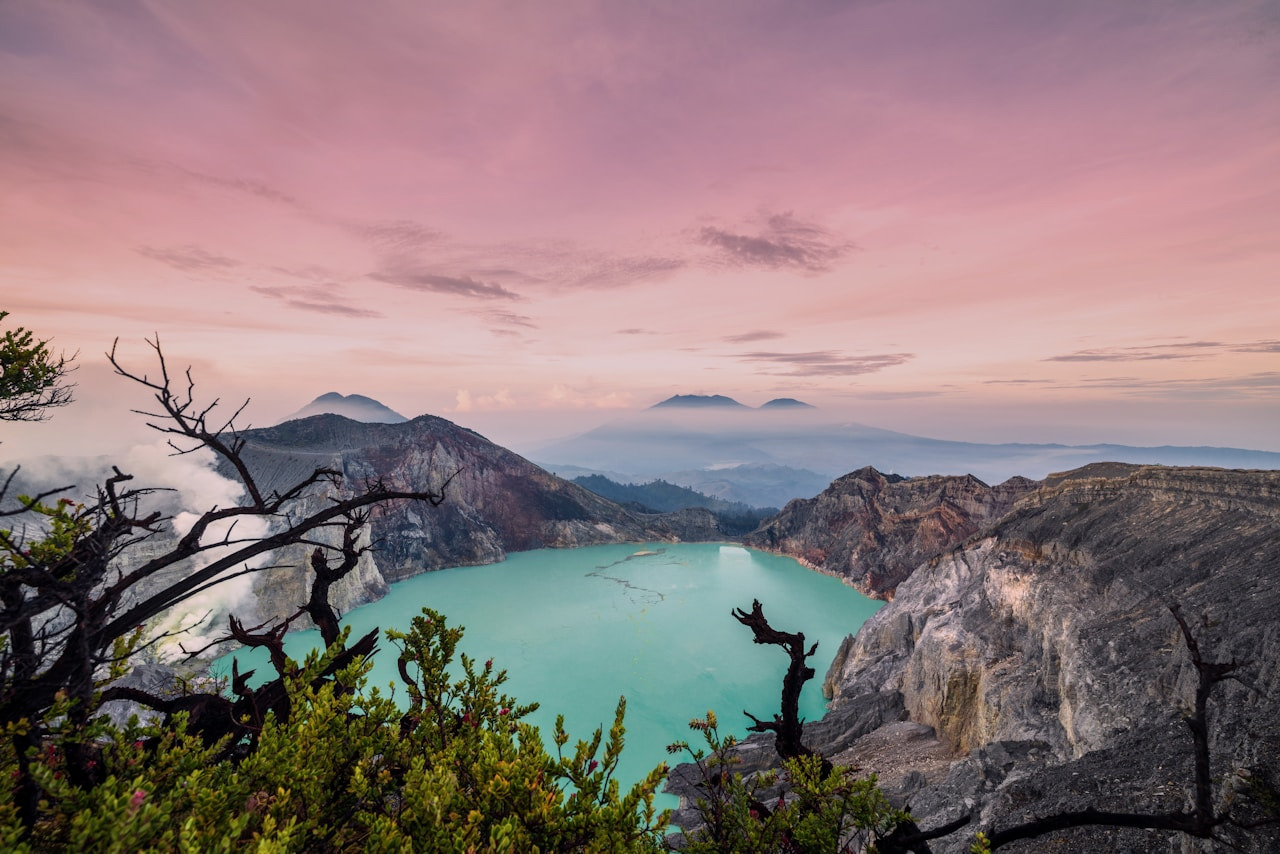 A turquoise volcanic crater lake surrounded by rocky cliffs under a soft pink sky, Ultra