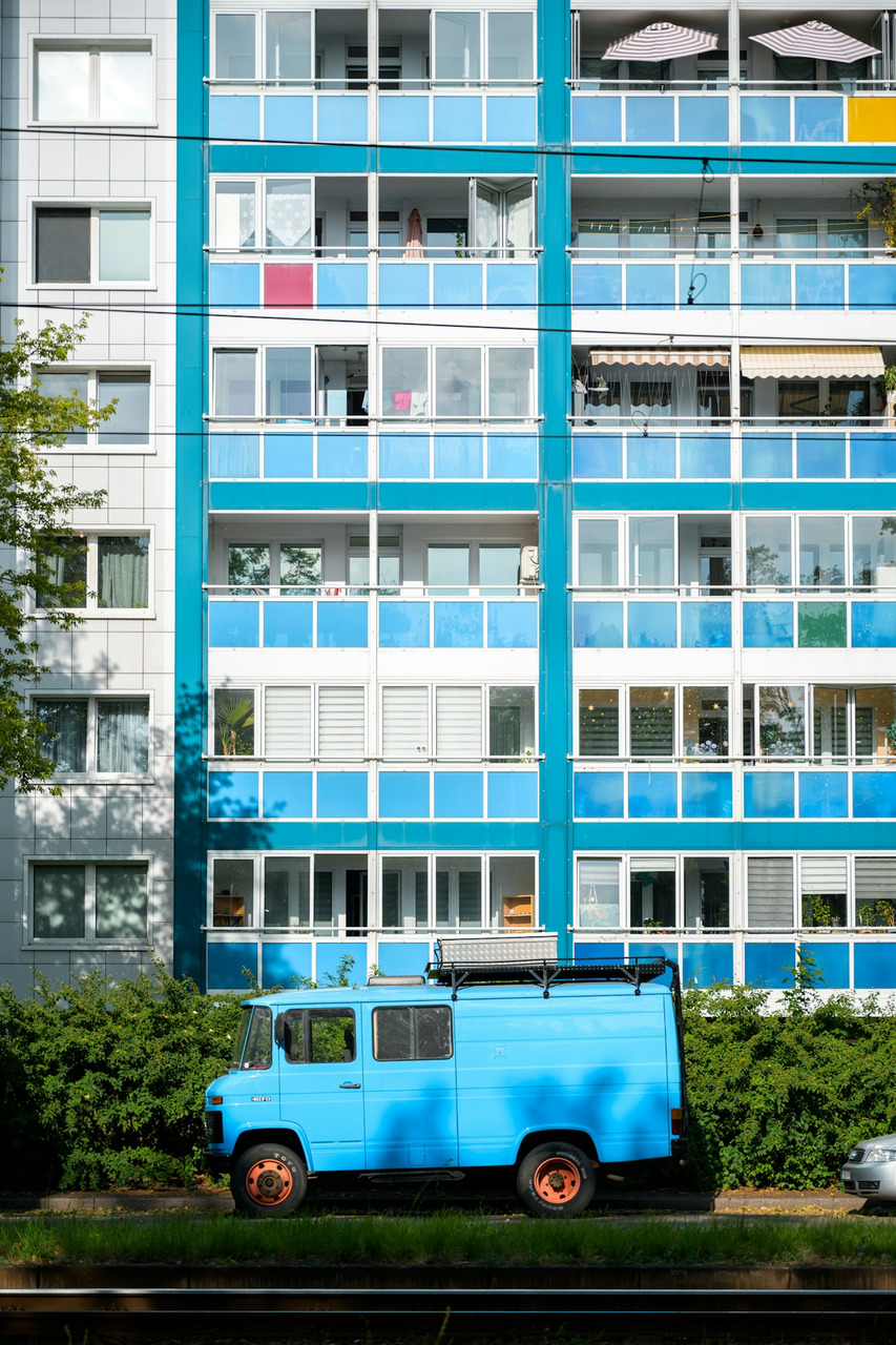 Bright blue van parked against a modern apartment building, Ultra