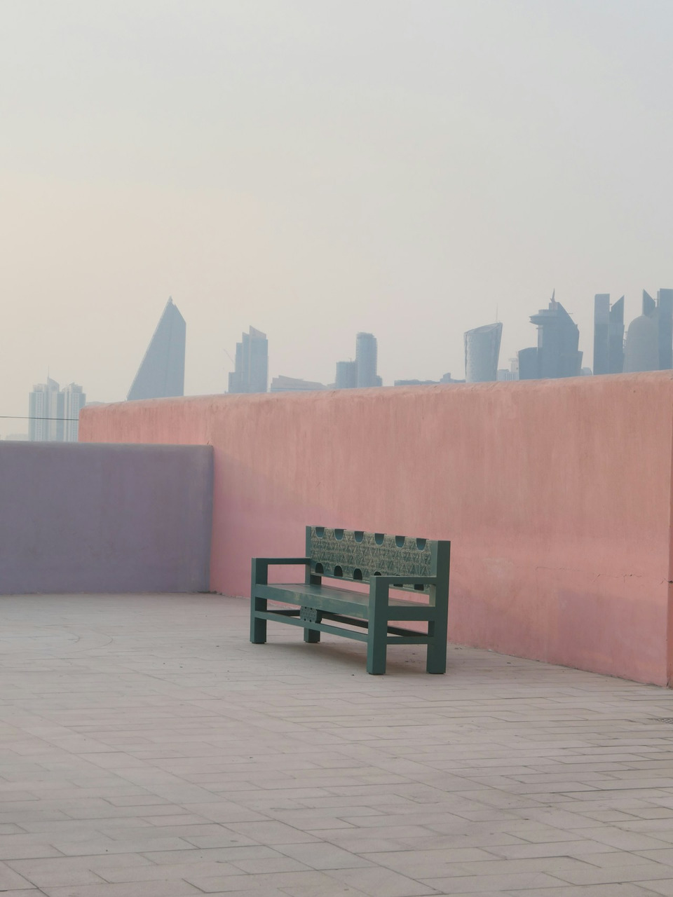 Green bench against pink wall, hazy city skyline, Ultra