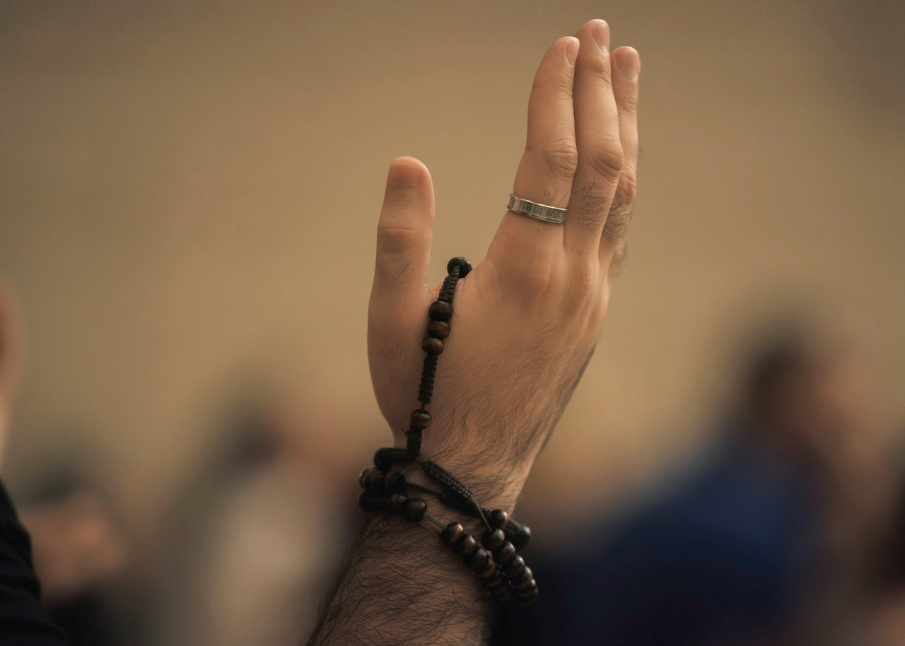 Man's hands holding prayer beads, raised in supplication, Ultra