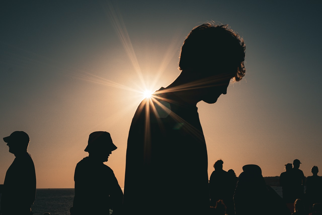 Silhouettes of people against a bright low sun in a clear sky, Ultra