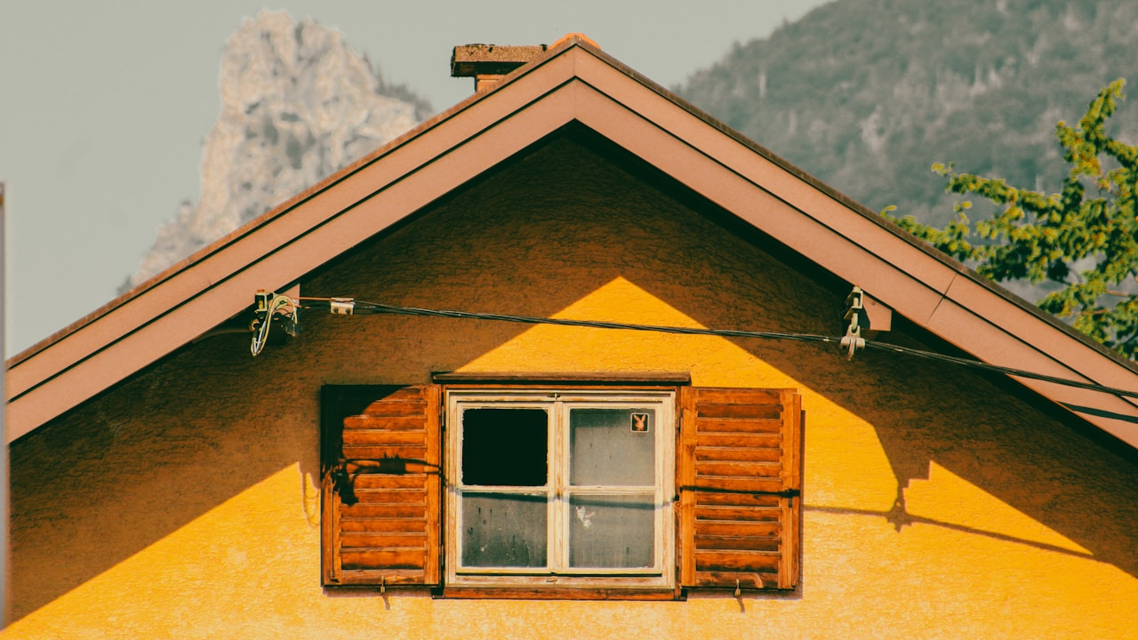 Yellow house with wooden shutters and mountain in background, Ultra